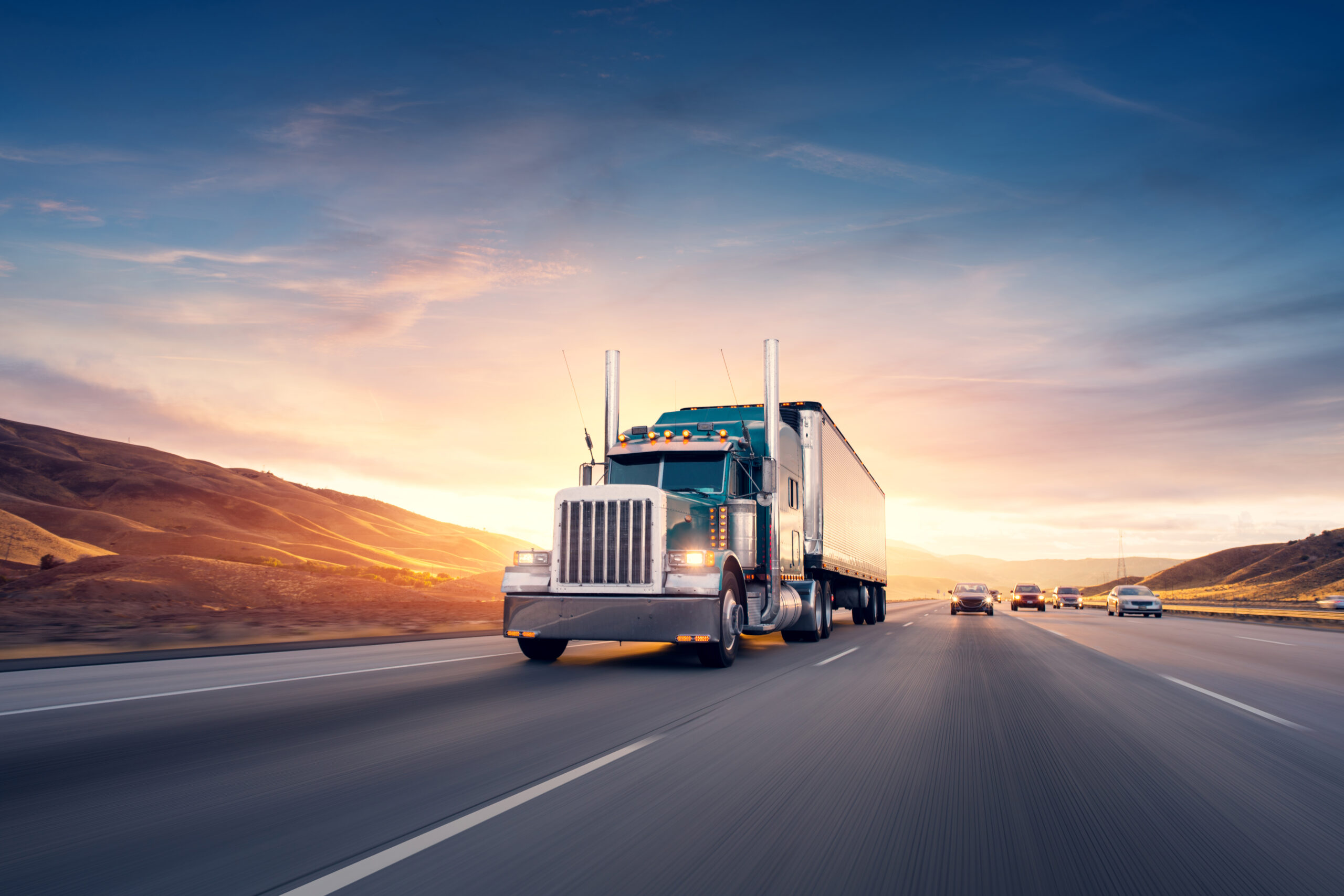 semi driving down the highway with a sunset in the background