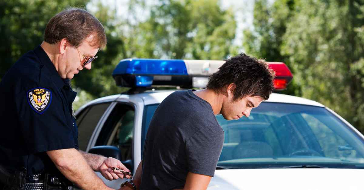 A young man being arrested by a police officer