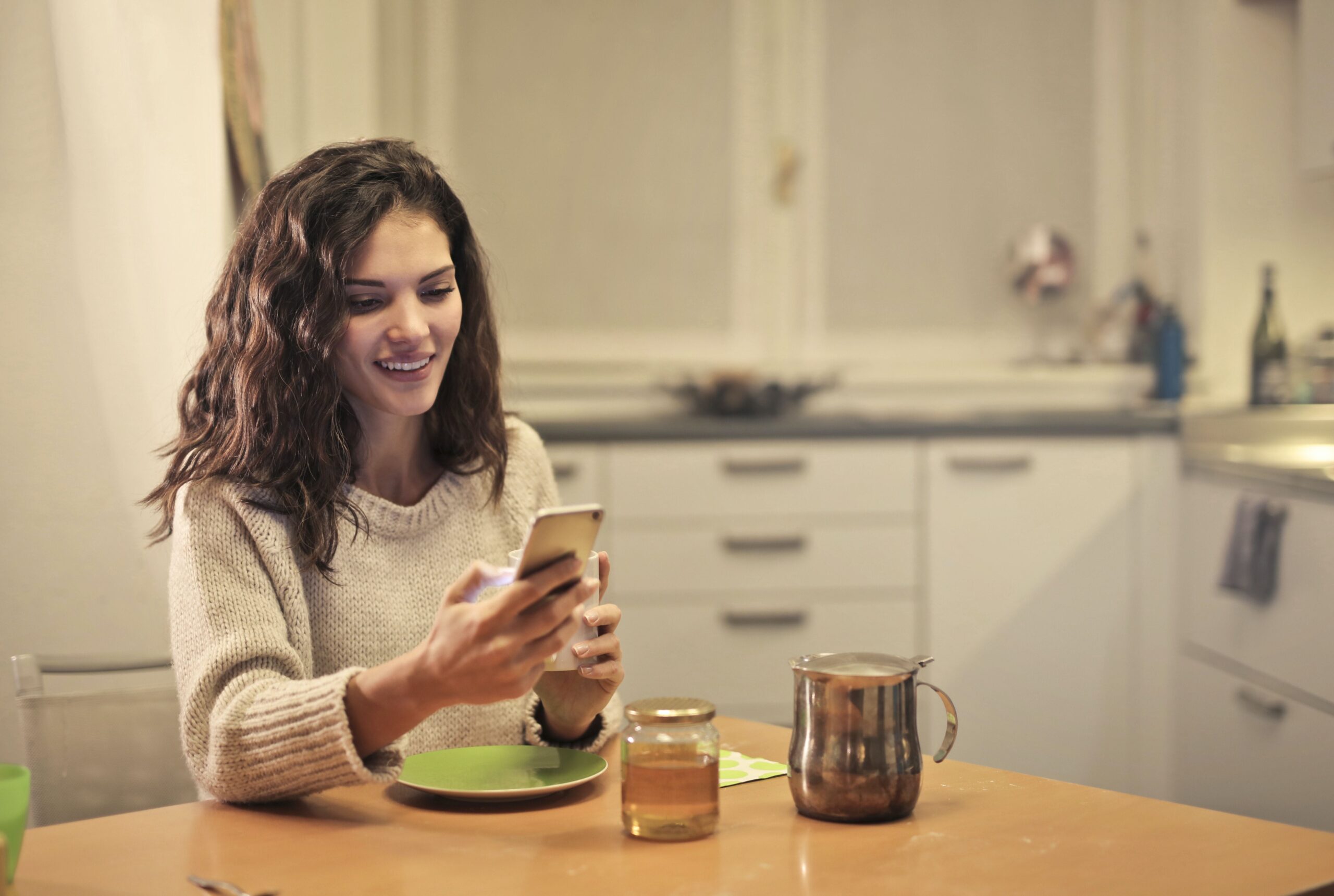 woman smiling looking at phone in kitchen
